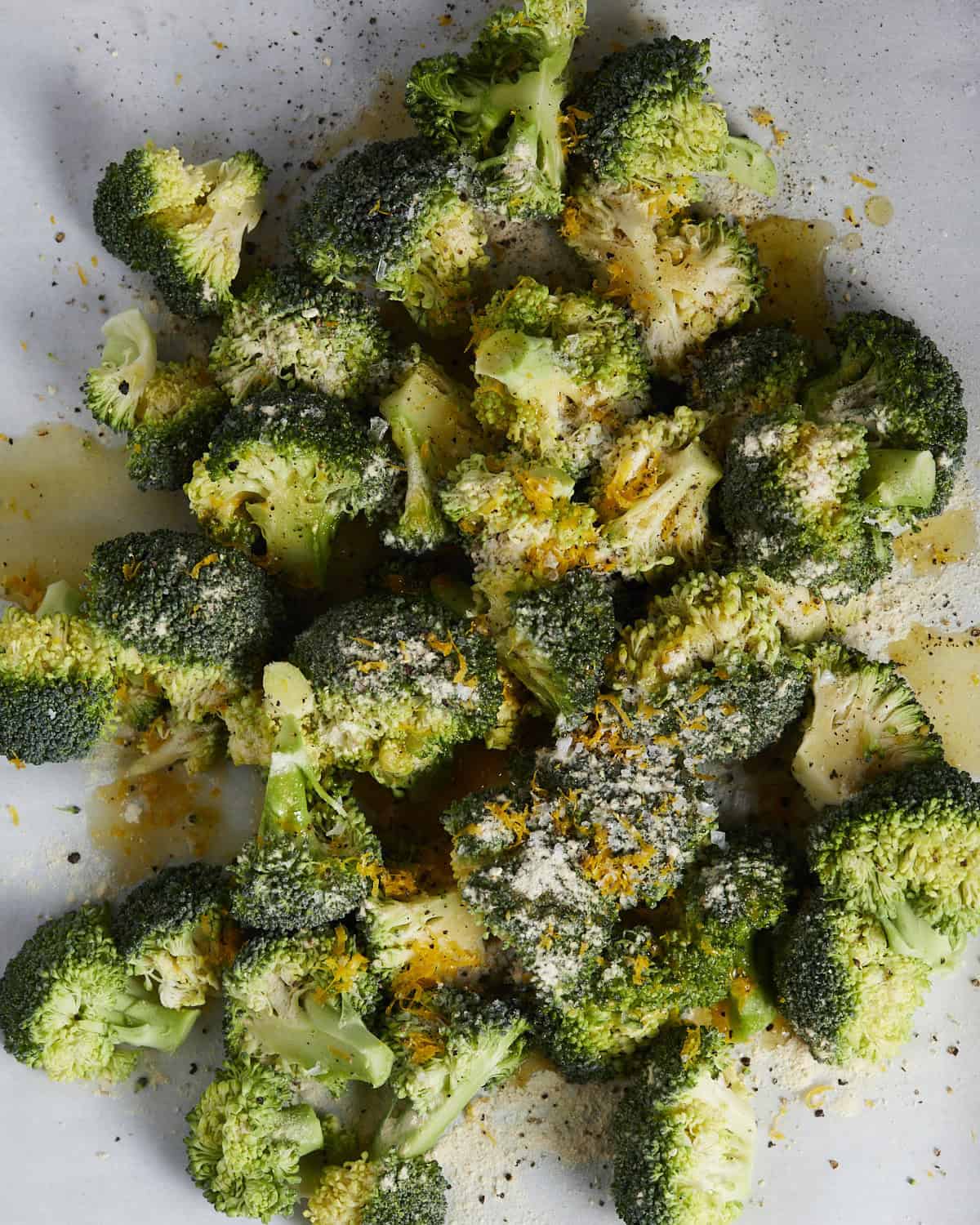 Adding broccoli to a sheet pan with seasonings and olive oil.