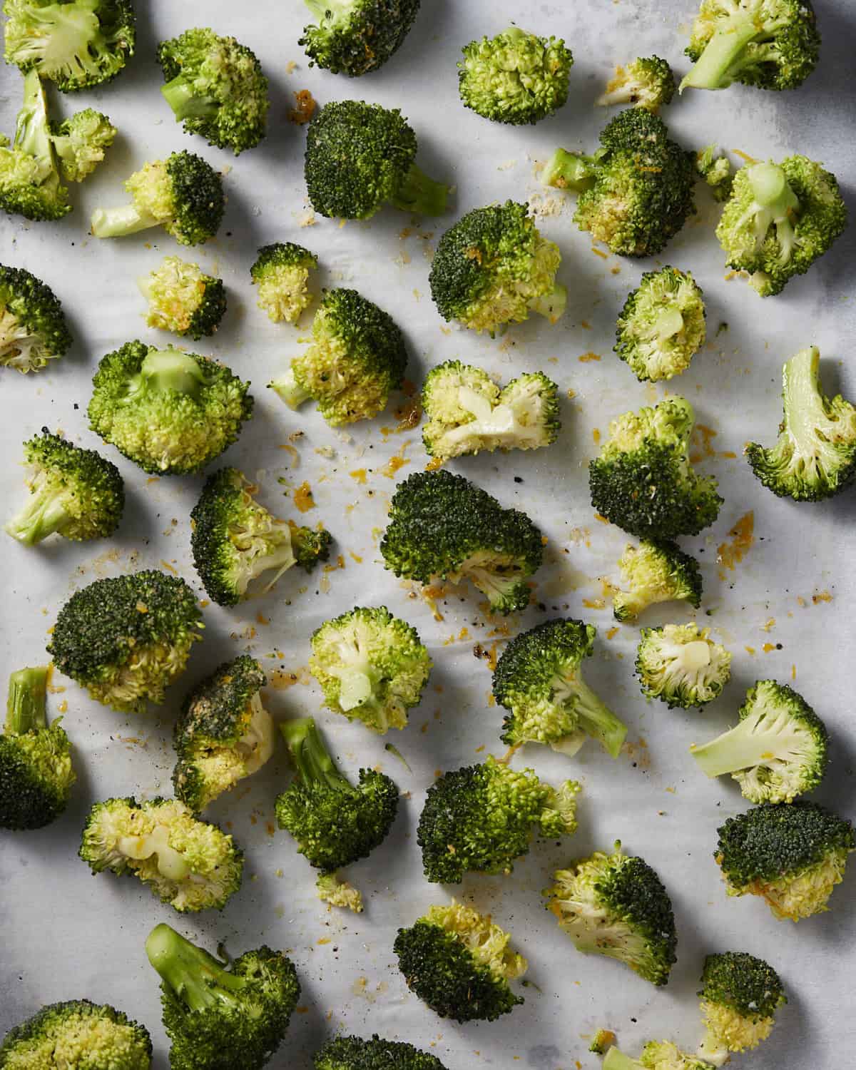 Broccoli tossed in seasonings and spread in an even layer on a sheet pan. 