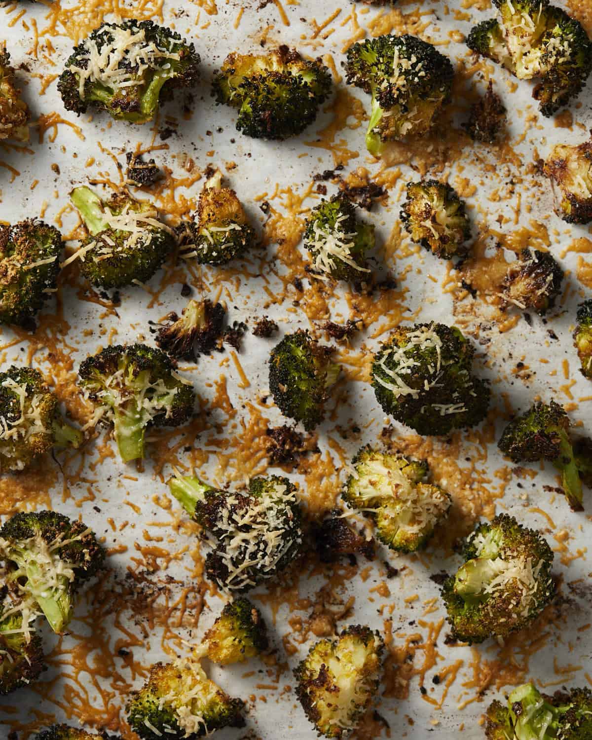 Roasted broccoli on a sheet pan with crispy parmesan.