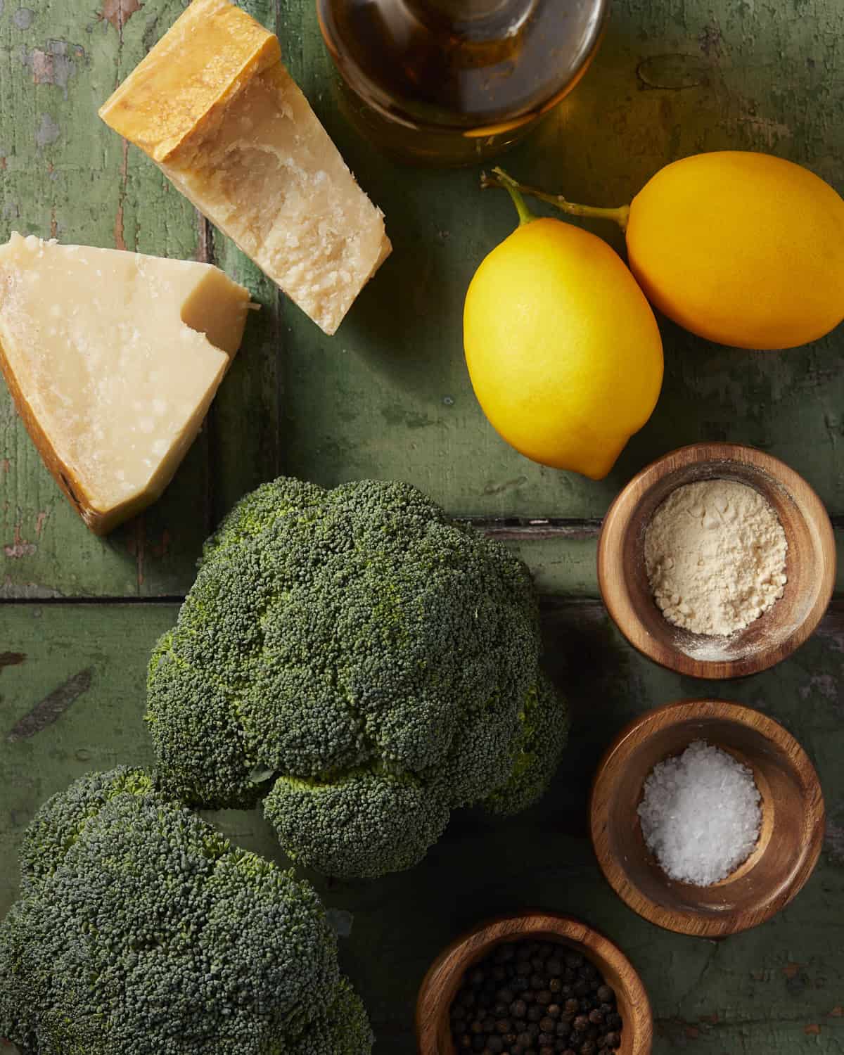 Ingredients needed to make roasted parmesan broccoli on a rustic green background.
