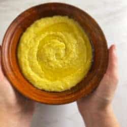 Creamy Polenta in a wooden bowl with hands