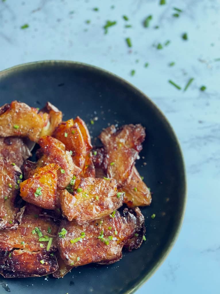 Smashed Potatoes served in a black bowl with chives.