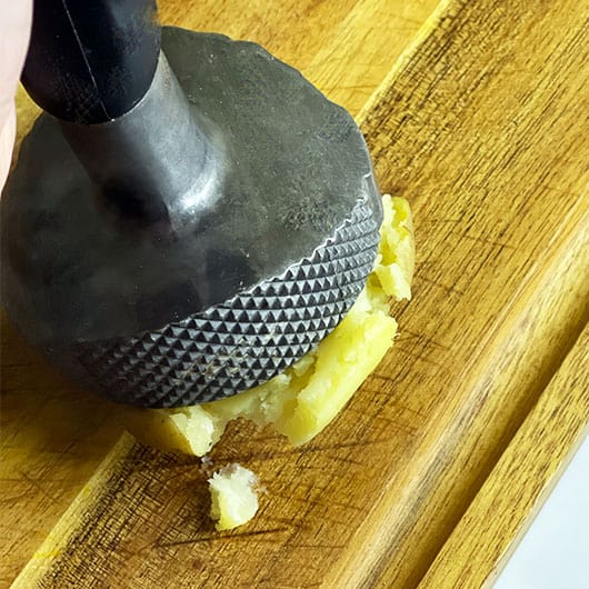 Smashing a parboiled potato to make some crispy smashed potatoes.