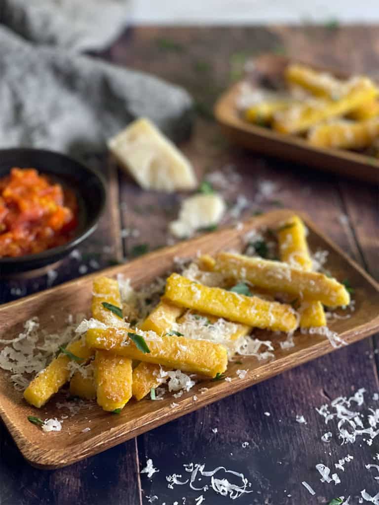 Polenta Fries served in wooden plates with tomato sauce and cheese