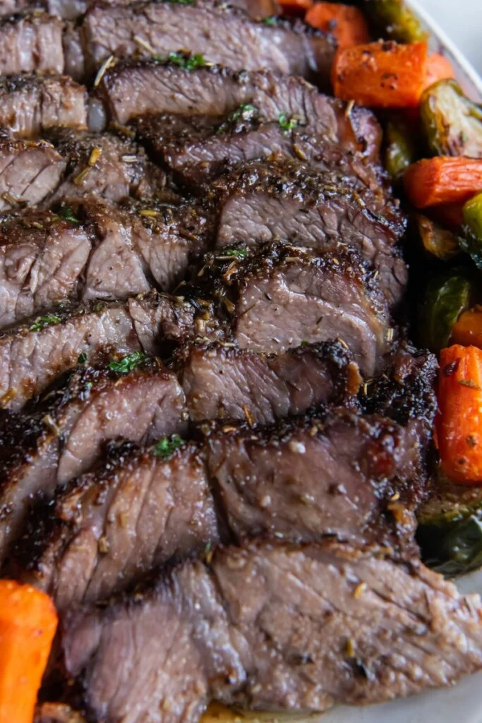 Close up of sliced chuck roast with roasted carrots