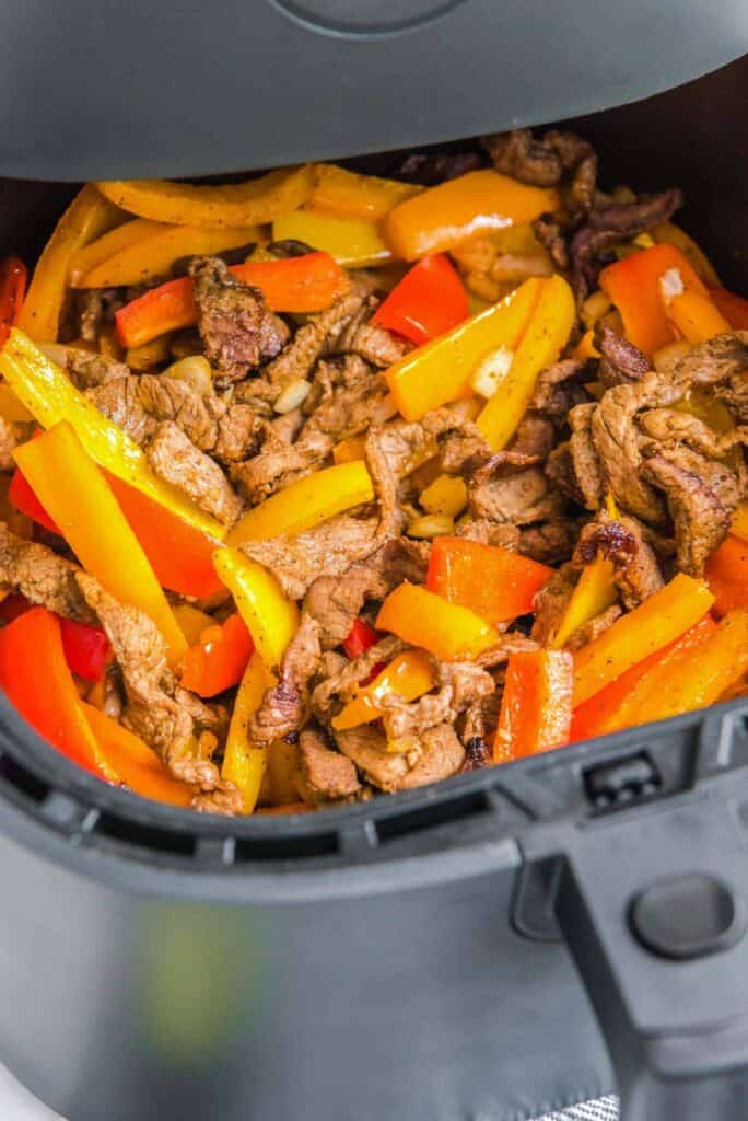 Steak strips in air fryer with peppers and onios