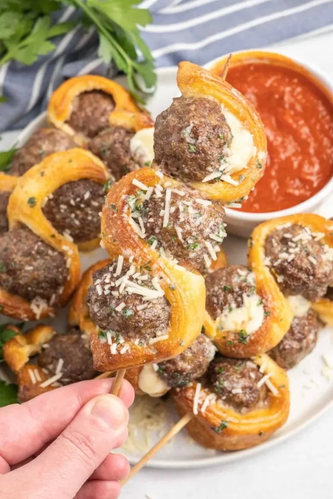 Meatballs on skewers with pastry.  Bowl of tomato dipping sauce on the side.