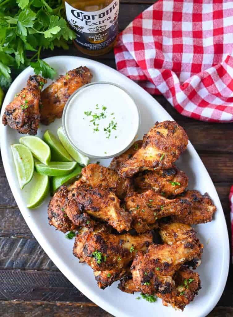 Air-fryer-old-bay-chicken-wings- on a plate served with ranch dressing and limes