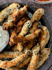 Portobello mushroom fries breaded and cooked to golden brown on a serving try with a creamy dipping sauce and a pizza sauce.