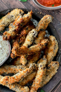 Portobello mushroom fries breaded and cooked to golden brown on a serving try with a creamy dipping sauce and a pizza sauce.