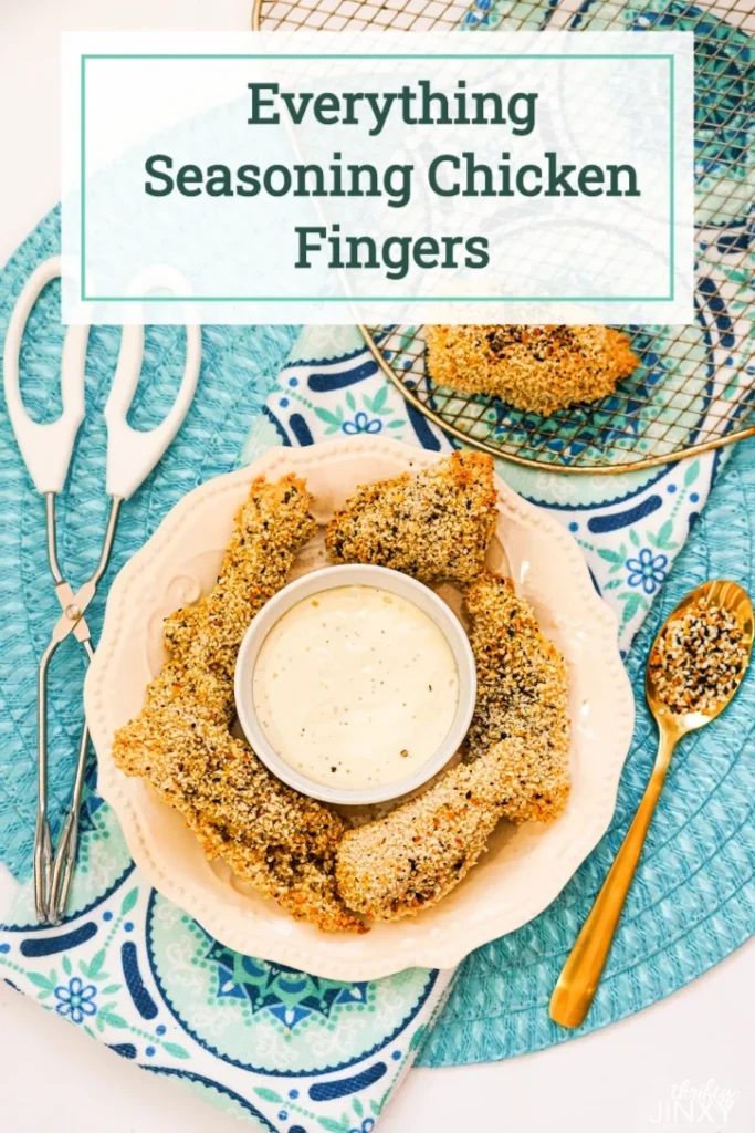 Air fryer chicken fingers on a plate with ranch dressing dip in the middle.  Blue tablecloth background with gold spoon.