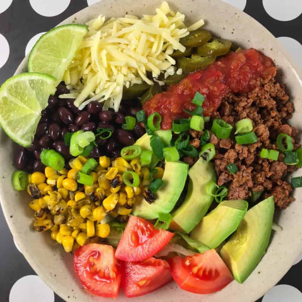 Taco salad with ground beef, cheese, avocado, corn, black beans and tomatoes