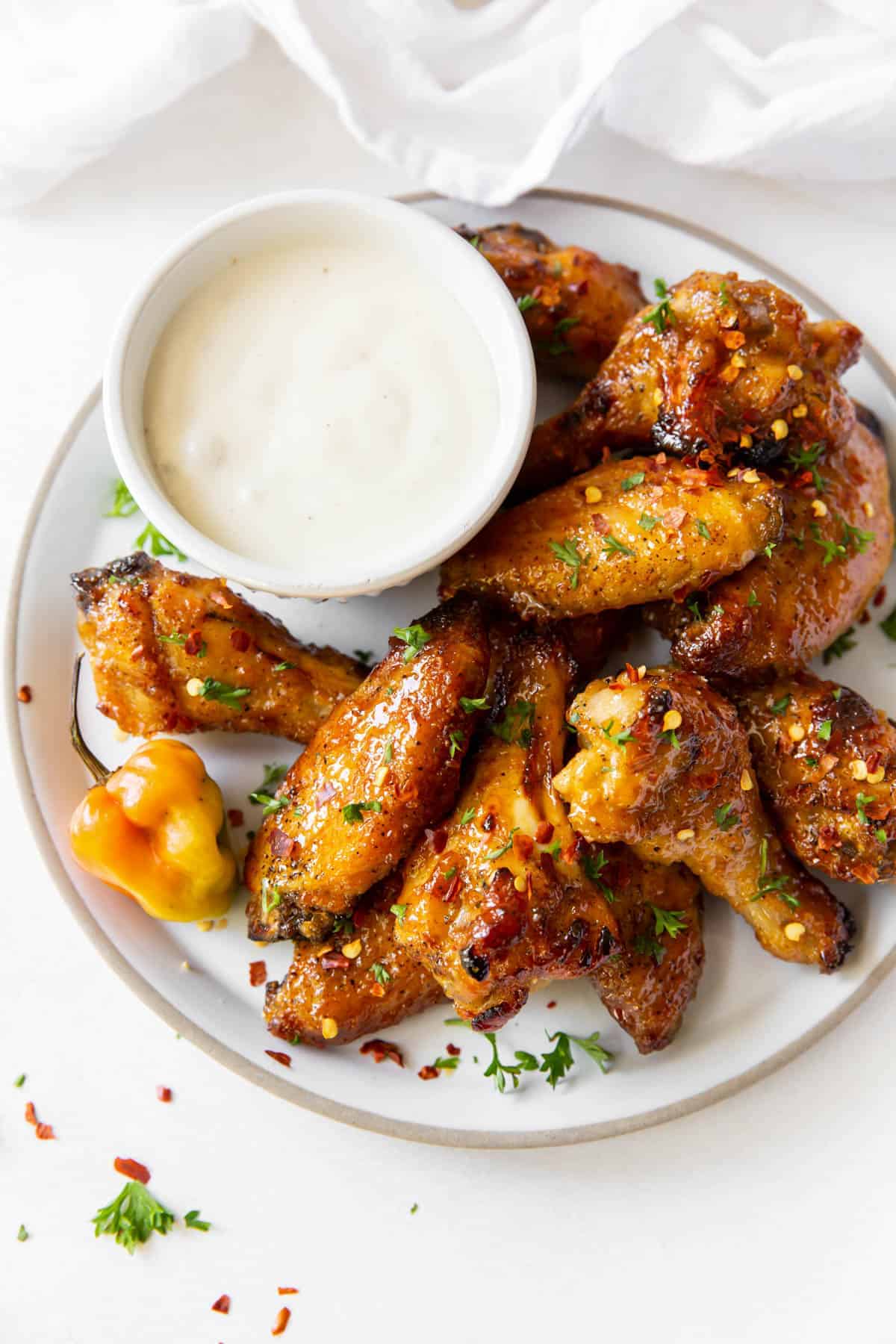 Wings on a white plate with white dipping sauce. 