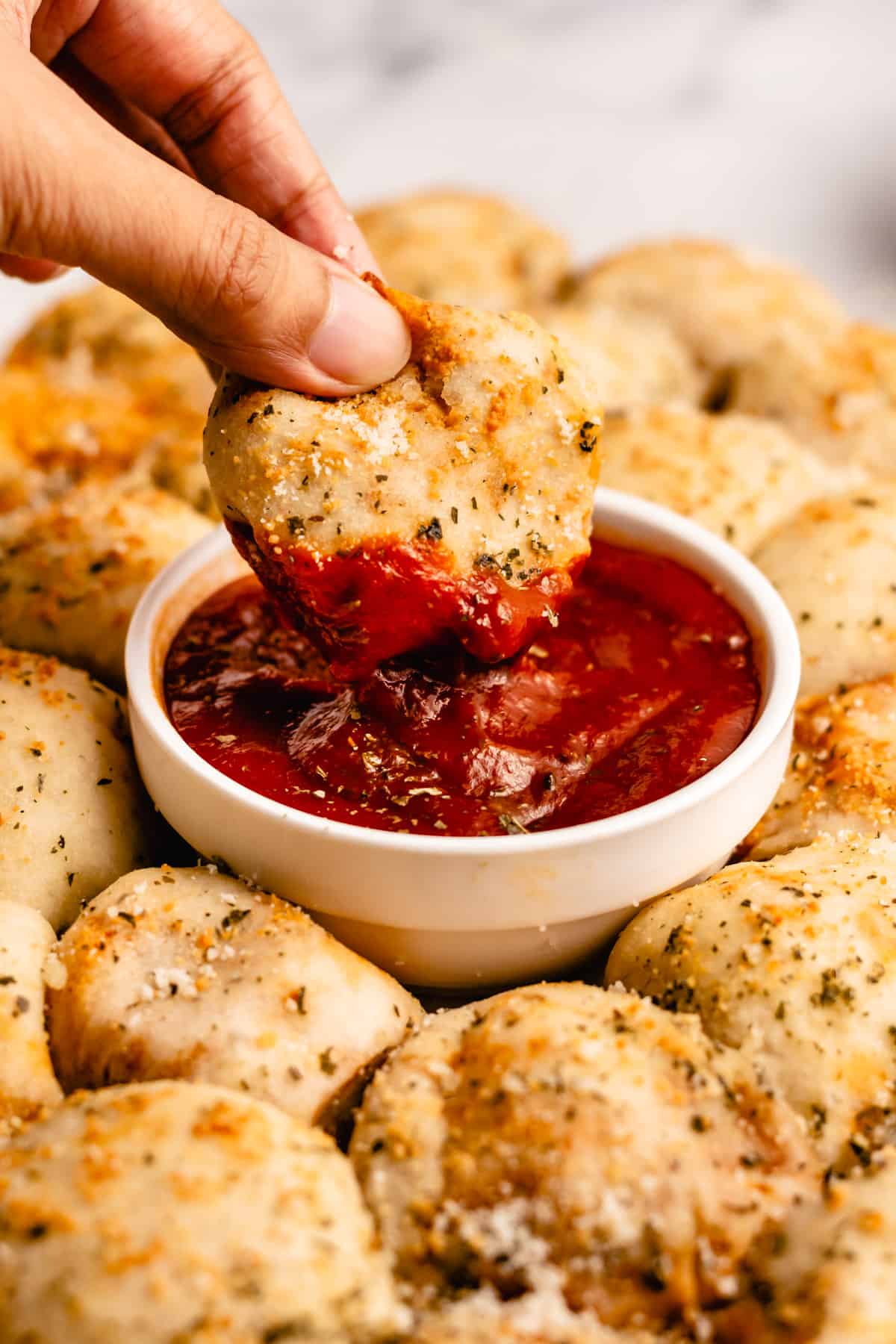 Pizza poppers on a plate.  One being dipped into a bowl of tomato sauce.