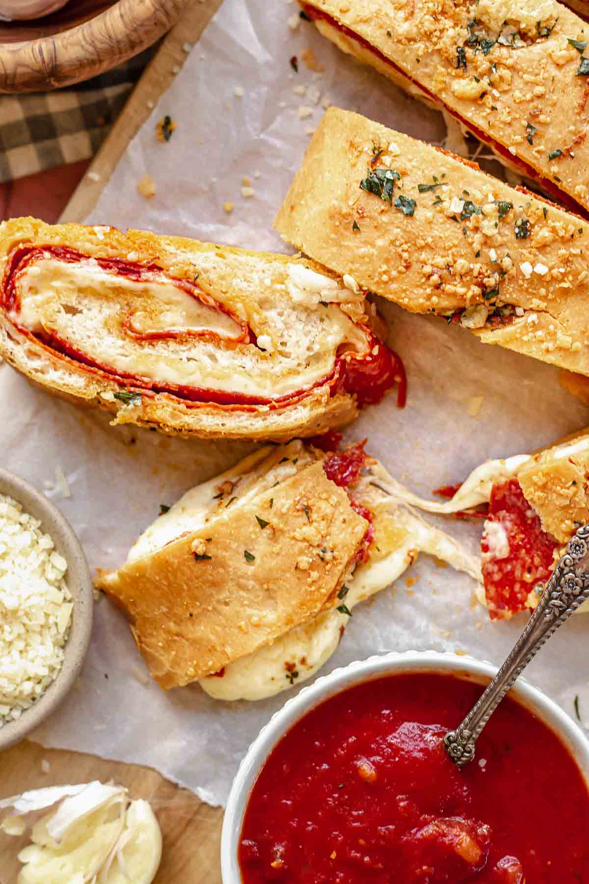 Bread rolled and filled with pepperoni and cheese on parchment paper.  