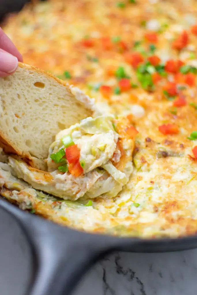 Crab dip with toast picking up dip.