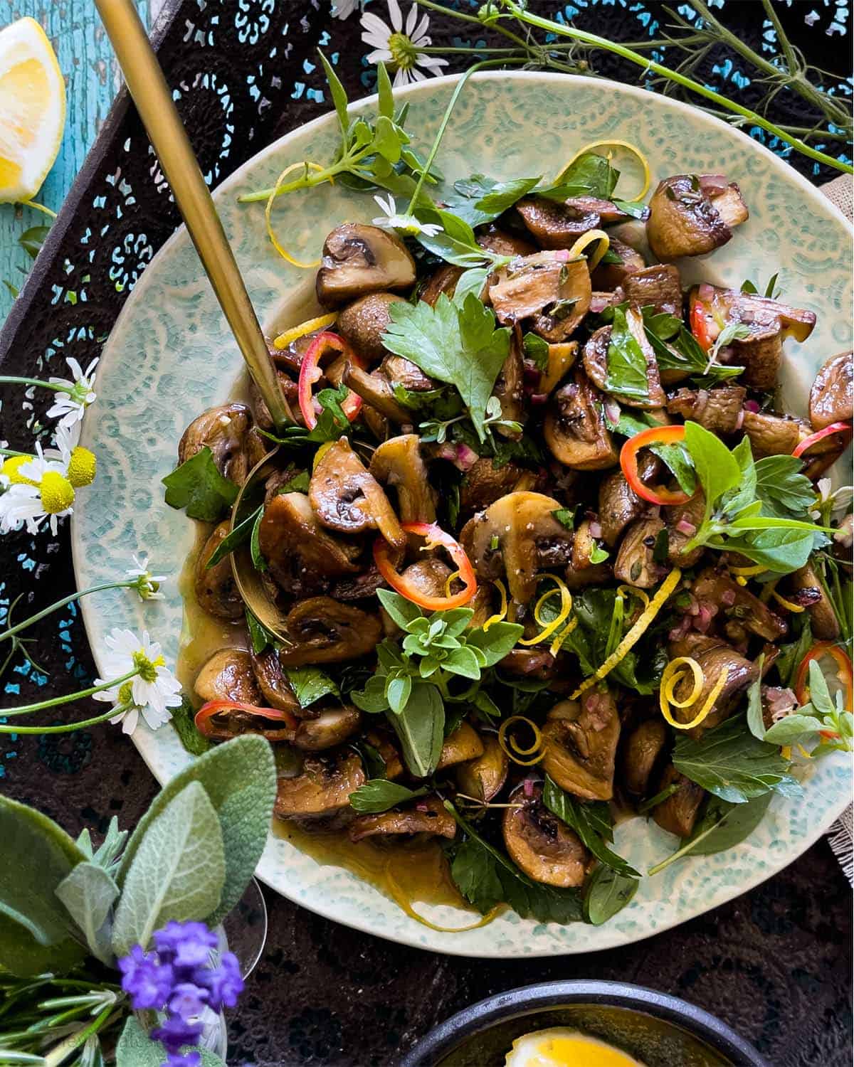 Mushroom salad served on a decorative blue plate and served with a gold spoon.