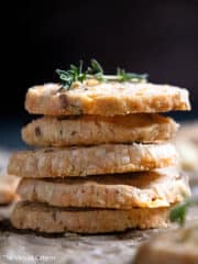 Stack of savory shortbread cookies topped with fresh thyme.