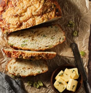 Sliced bread on crumbled parchment paper served with a side of butter and knife.