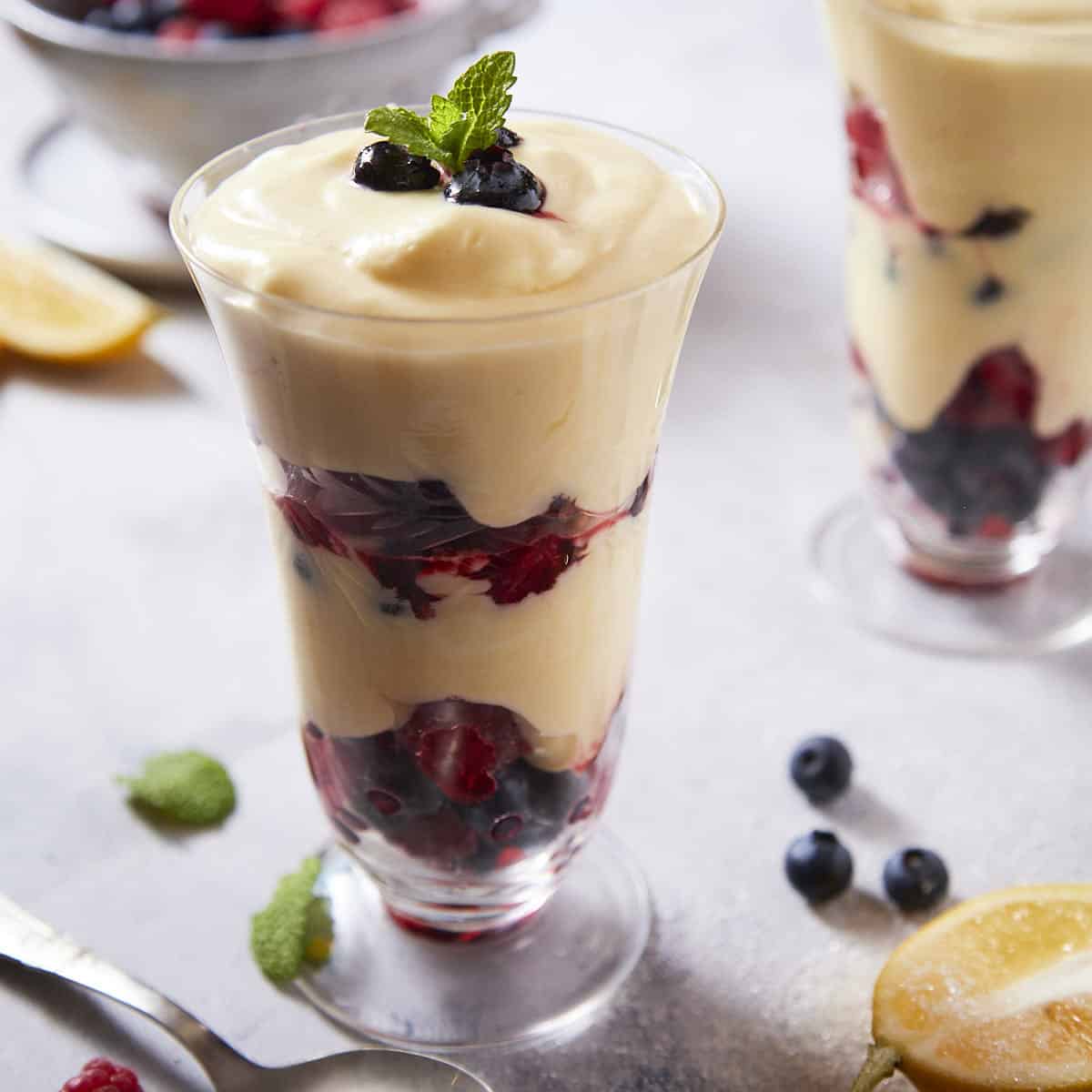 Layered berries and lemon cream in a glass to make a parfait.