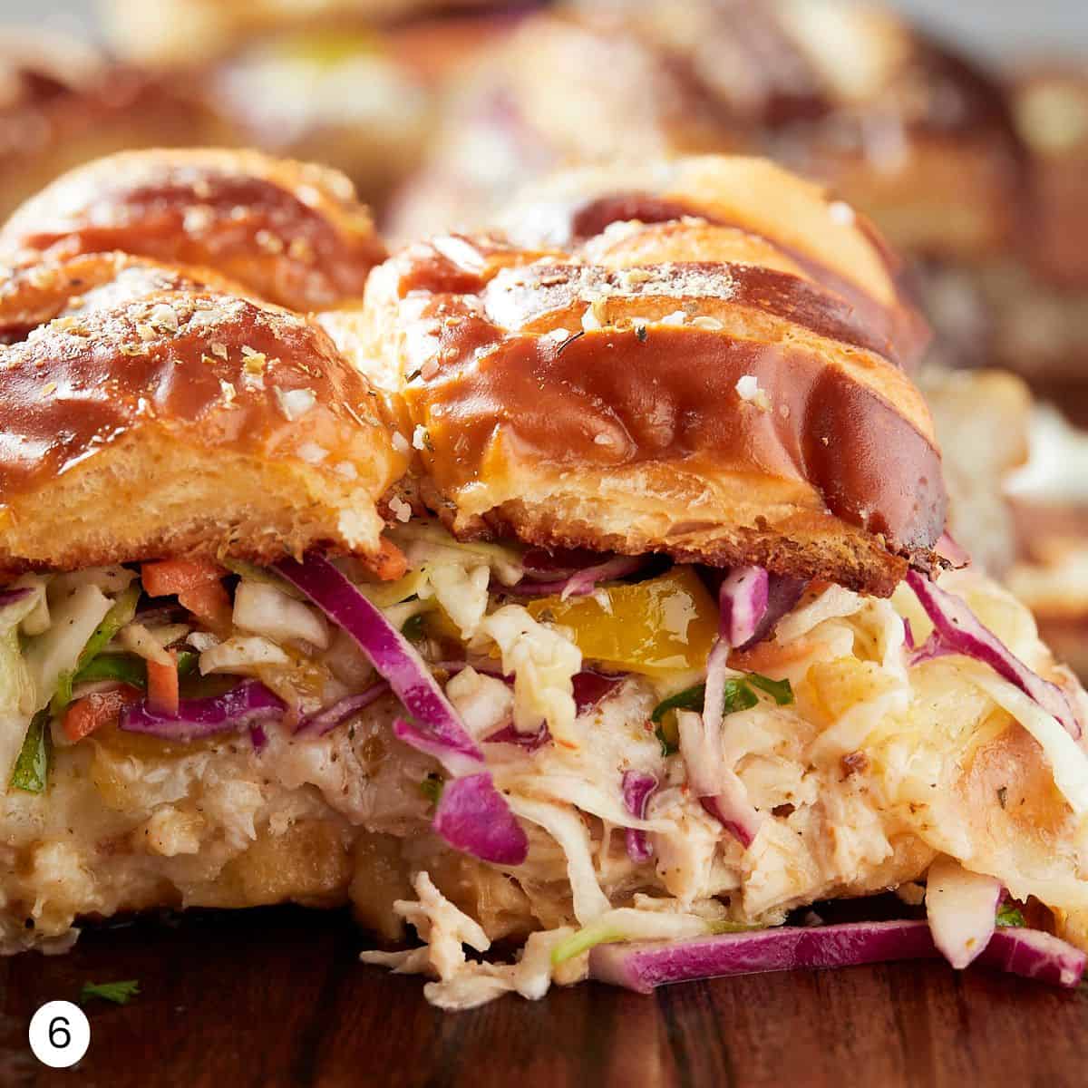 Assembled chicken sliders with coleslaw from a side view. 