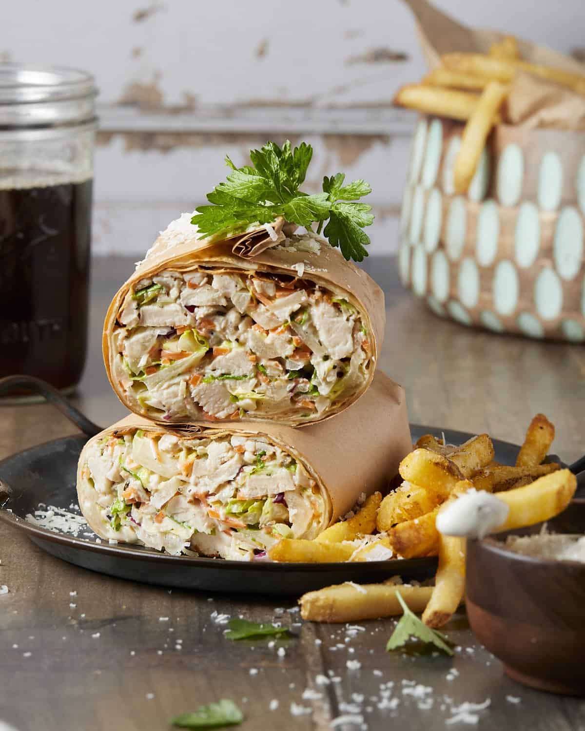 A chopped chicken Caesar wrap served with french fries and caesar dressing.