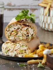 A chopped chicken Caesar wrap served with french fries and caesar dressing.