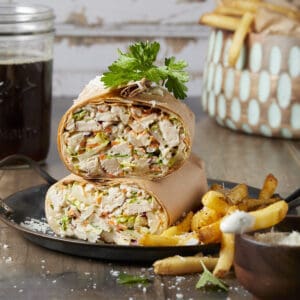 A chopped chicken Caesar wrap served with french fries and caesar dressing.