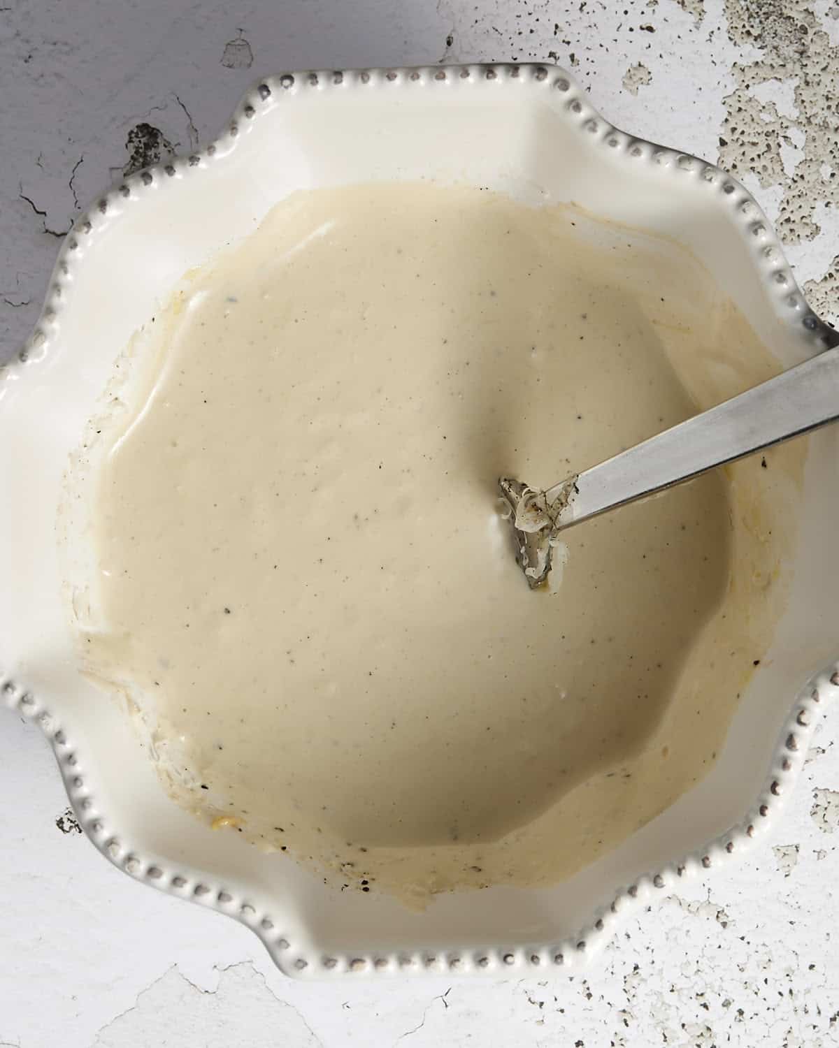 Caesar dressing mixed in a white bowl.