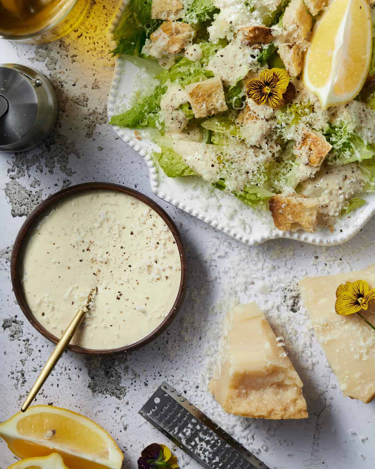 Easy Caesar dressing with mayo and a Caesar salad with parmesan cheese and croutons on a rustic background. 