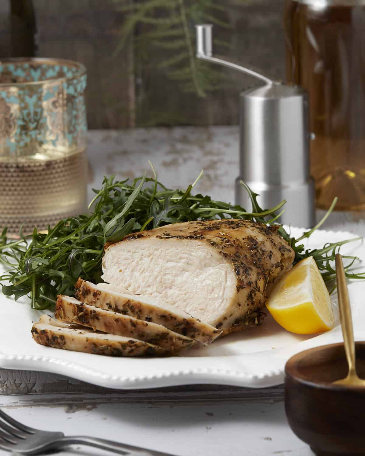 chicken breast sliced on a plate with an arugula salad.