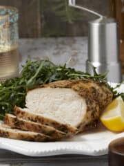 Juicy air fryer chicken breast sliced on a plate with an arugula salad.