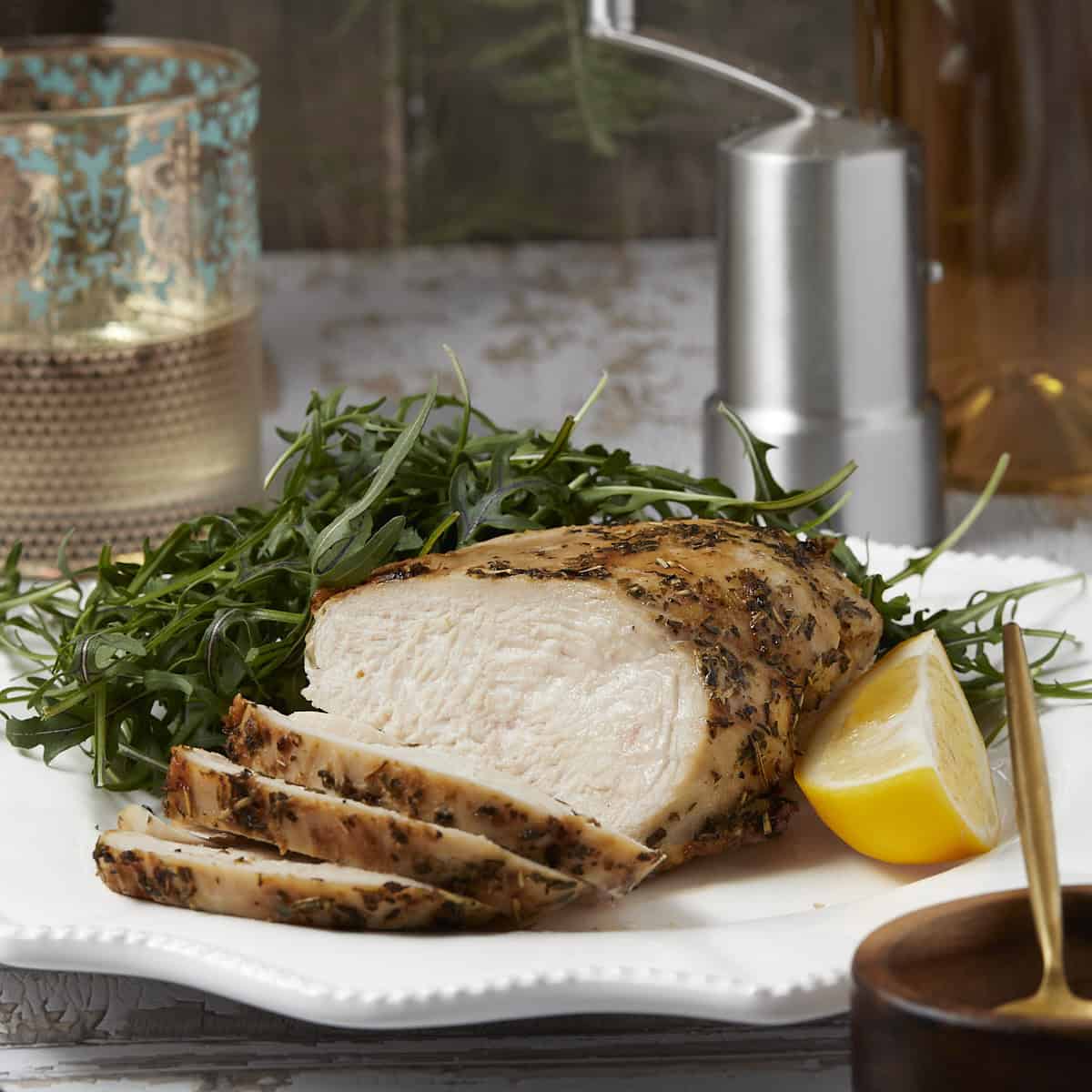 Juicy air fryer chicken breast sliced on a plate with an arugula salad. 