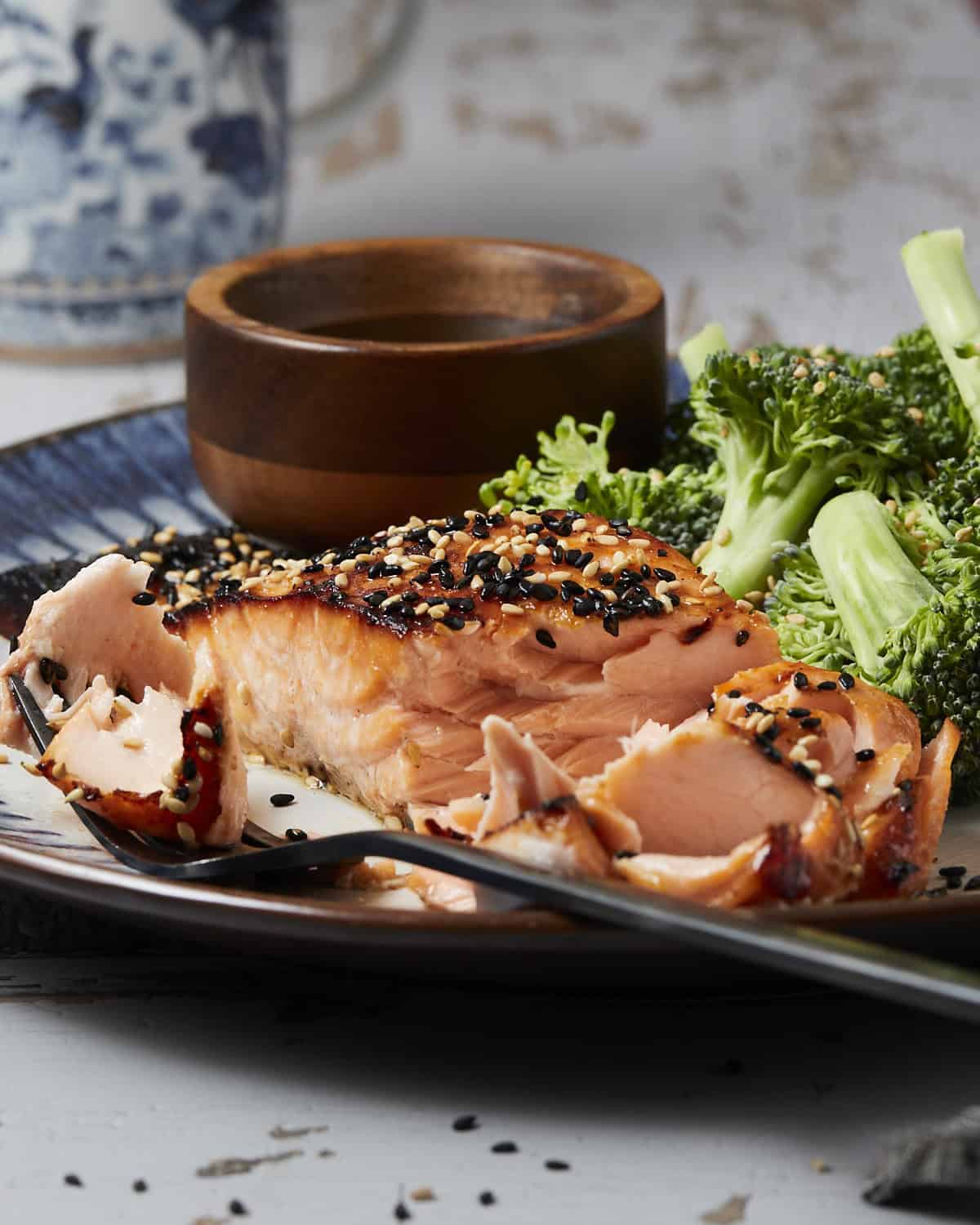 Up close of cooked salmon flaked with a fork on a plate. 