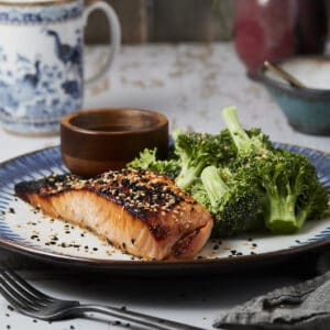 Broiled honey miso salmon on a plate with sesame seeds and broccoli.