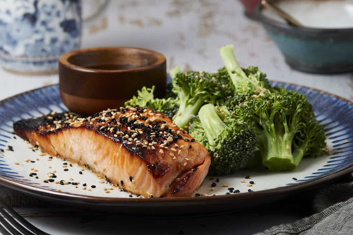 Broiled honey miso salmon on a plate with sesame seeds and broccoli.