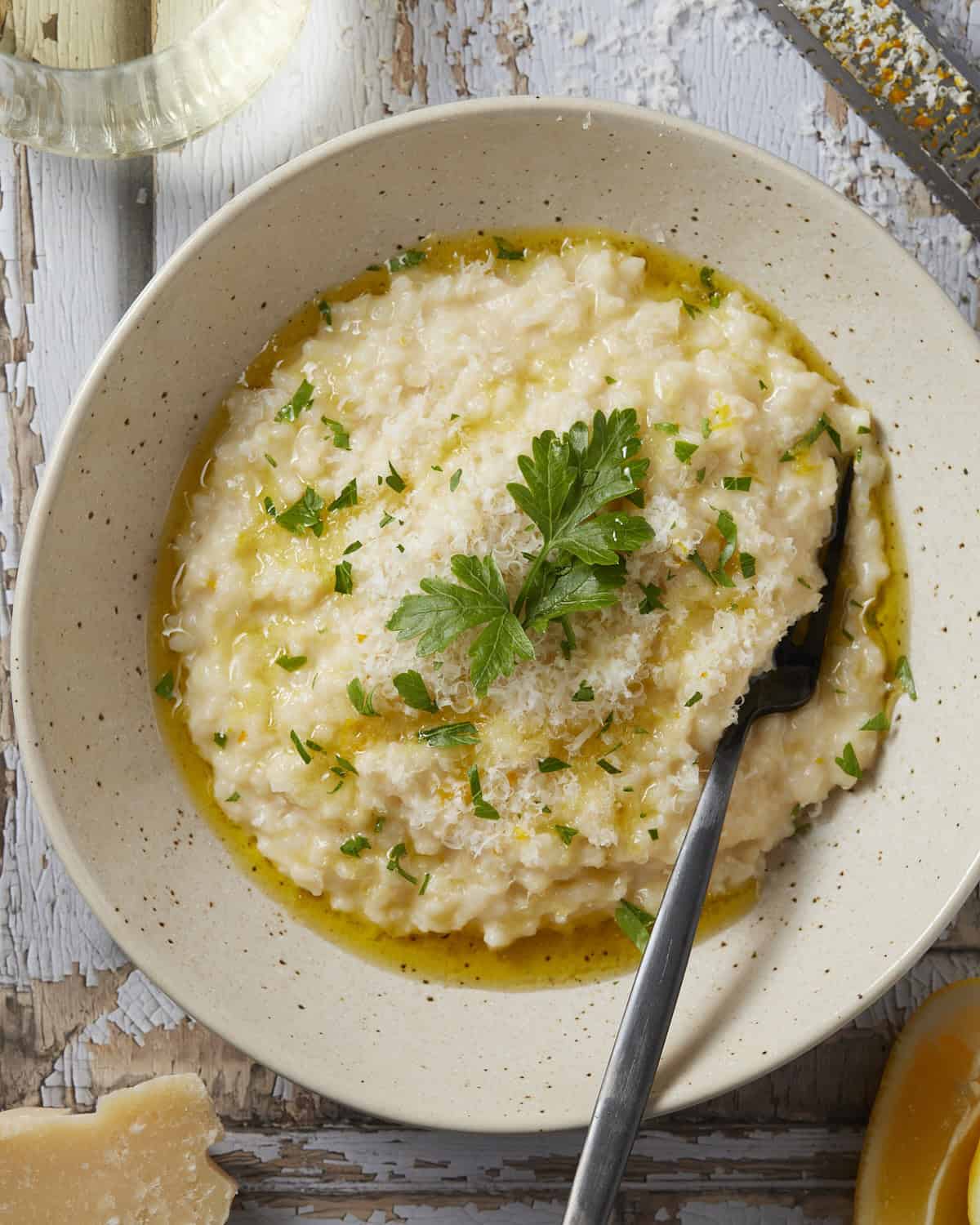 Easy oven-baked risotto in a bowl with parsley lemon and olive oil garnishes. 