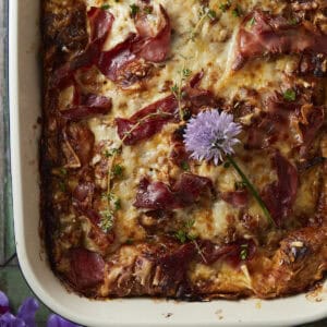French onion croissant bake in a baking dish with herbs on top.