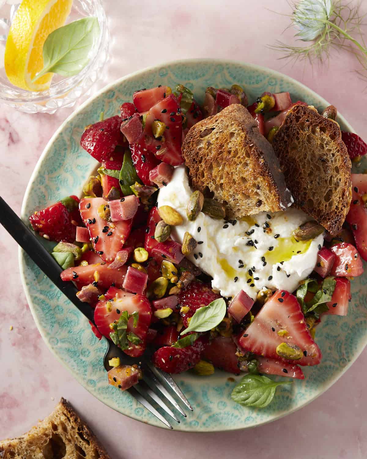A blue plate filled with strawberries, pickled rhubarb and burrata cheese.