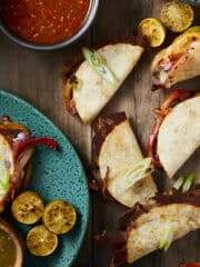 Steak fajita tacos on a wooden backdrop with a blue plate.