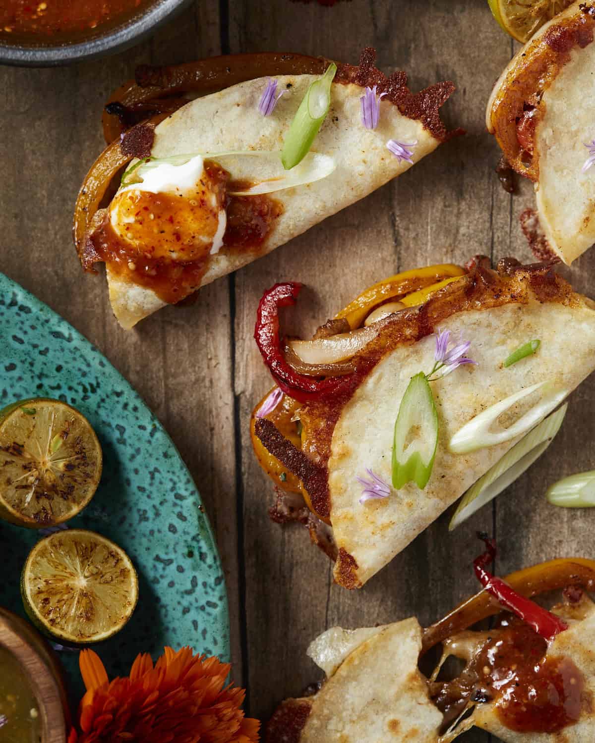 Steak fajita tacos up close with peppers, green onions and salsa.