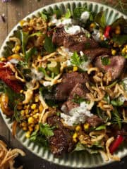 A blue bowl filled with steak salad with fried onions and blue cheese dressing.
