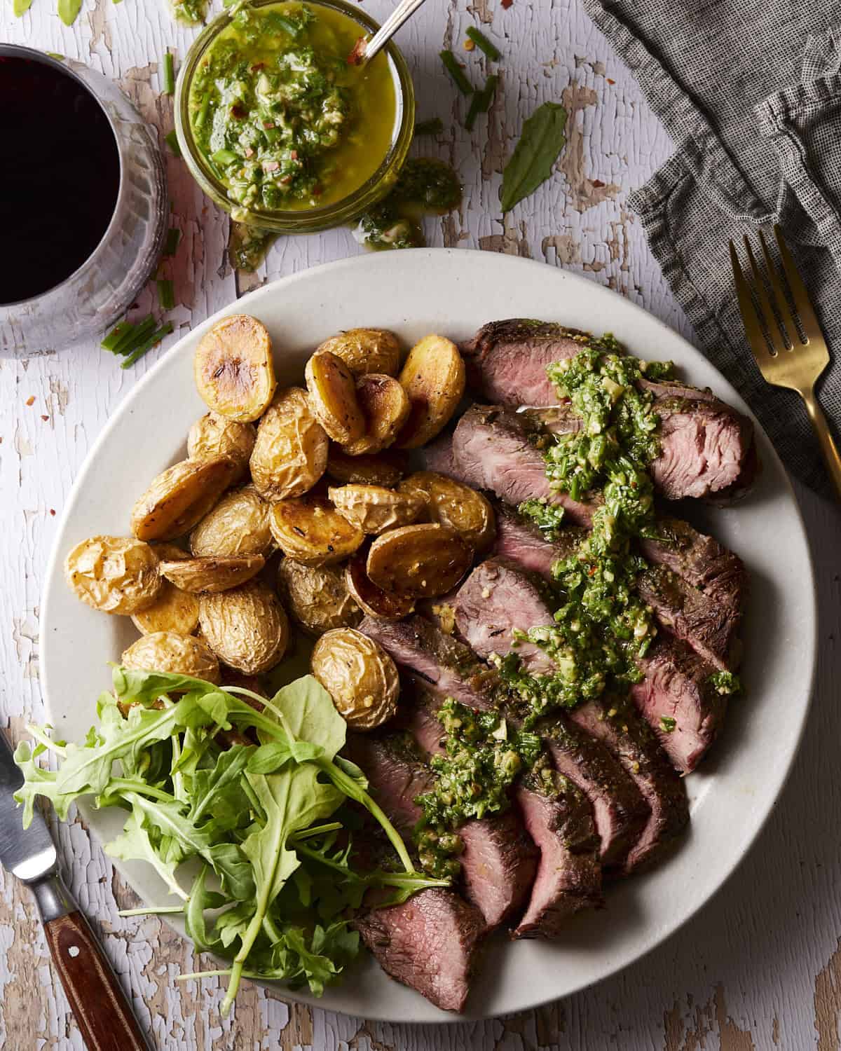 Chimichurri on steak with roasted potatoes and arugula.