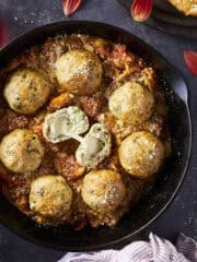 smoked meatballs with tomato sauce in a cast iron pan on a black background.