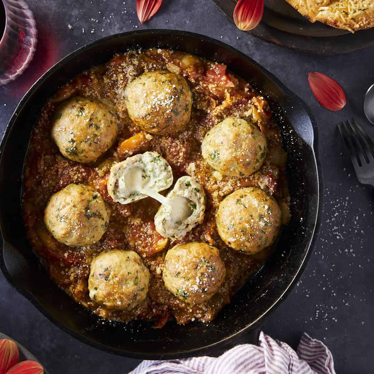 smoked meatballs with tomato sauce in a cast iron pan on a black background.