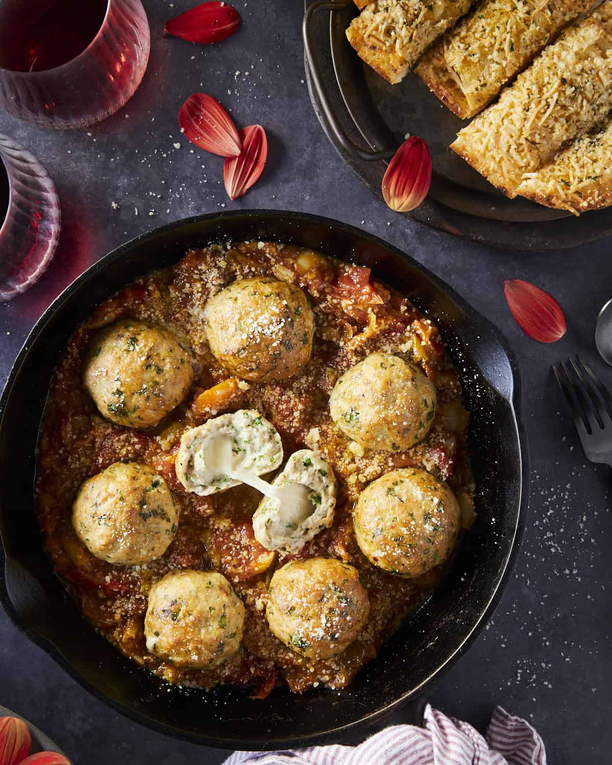 A cast iron pan filled with meatballs stuffed with cheese. 
