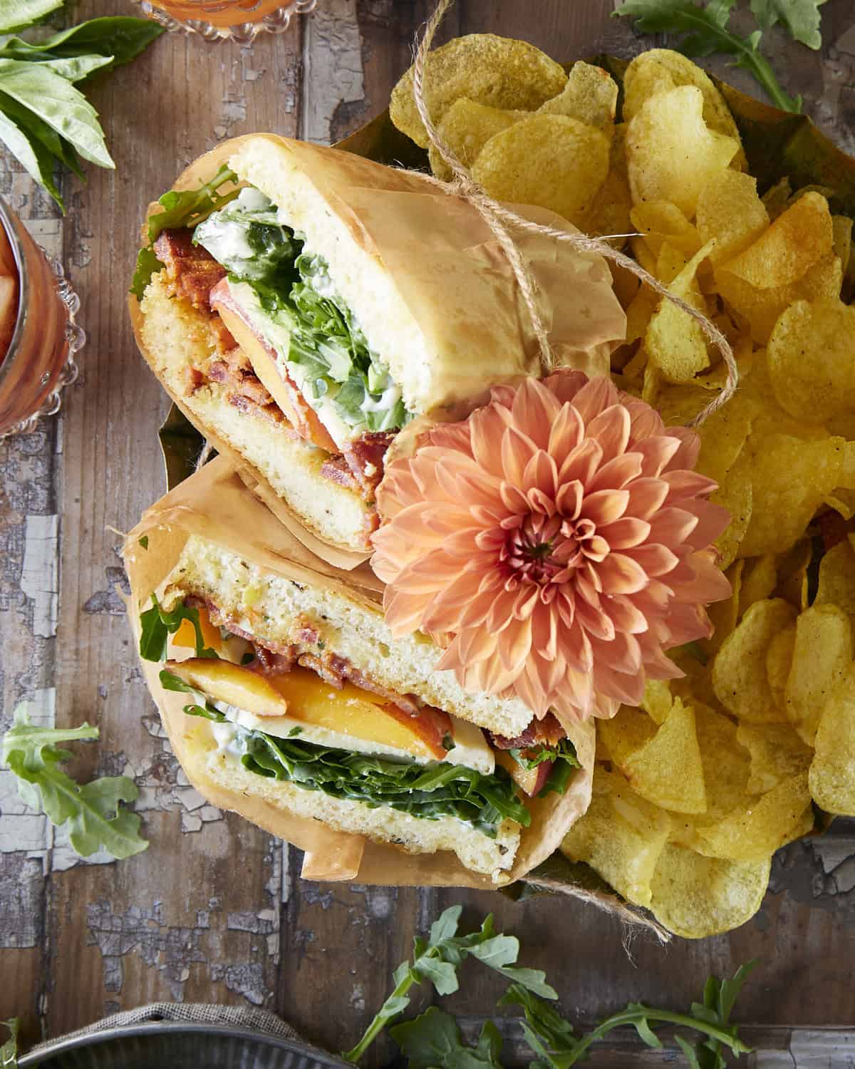 Sandwich with peaches, bacon and mayo with chips on rustic background,