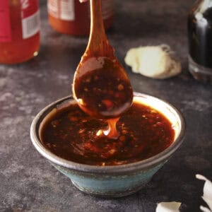 Sweet chili sauce in a bowl with a spoon, dripping the sauce into the bowl.