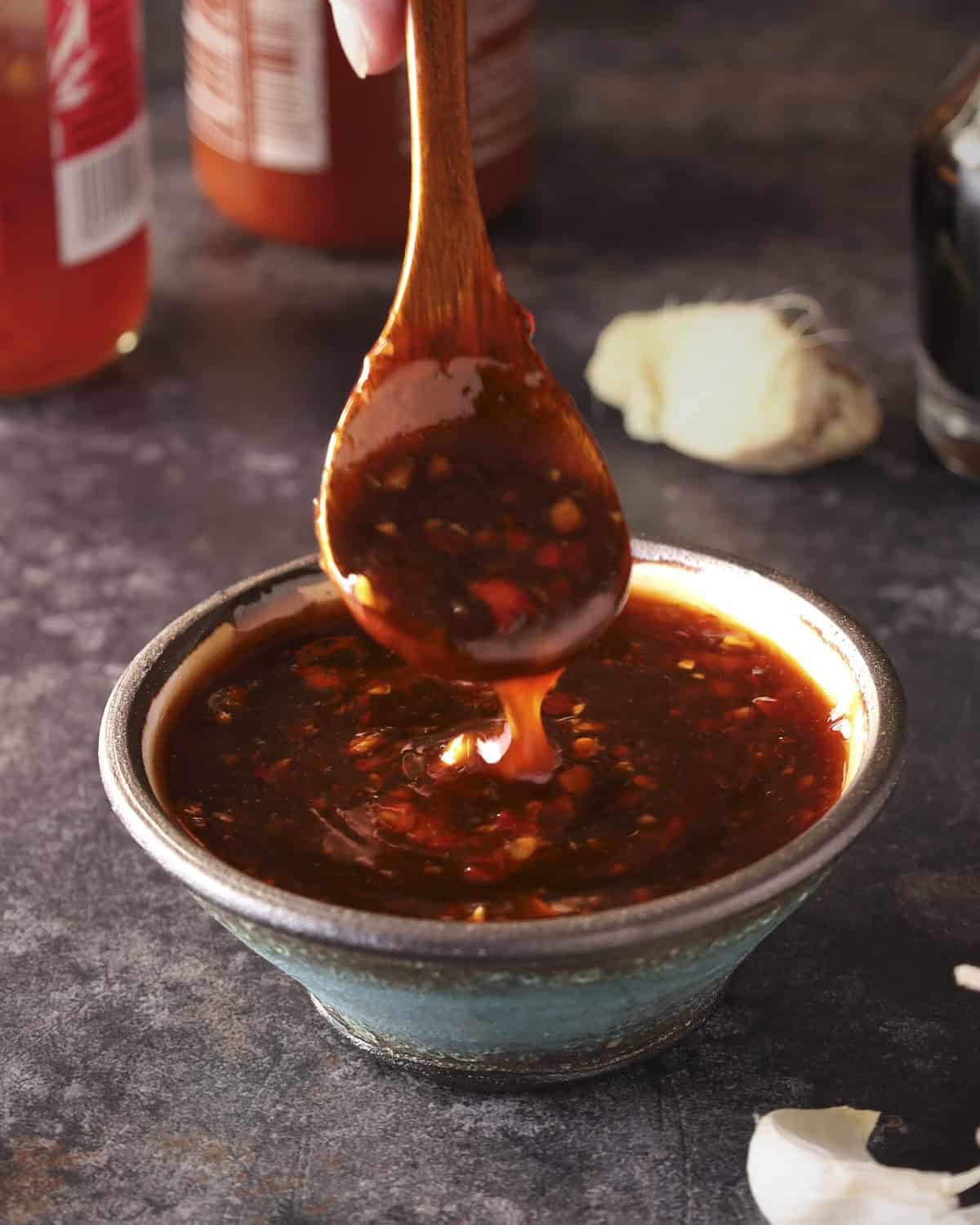 Sweet chili sauce in a bowl with a spoon, dripping the sauce into the bowl.