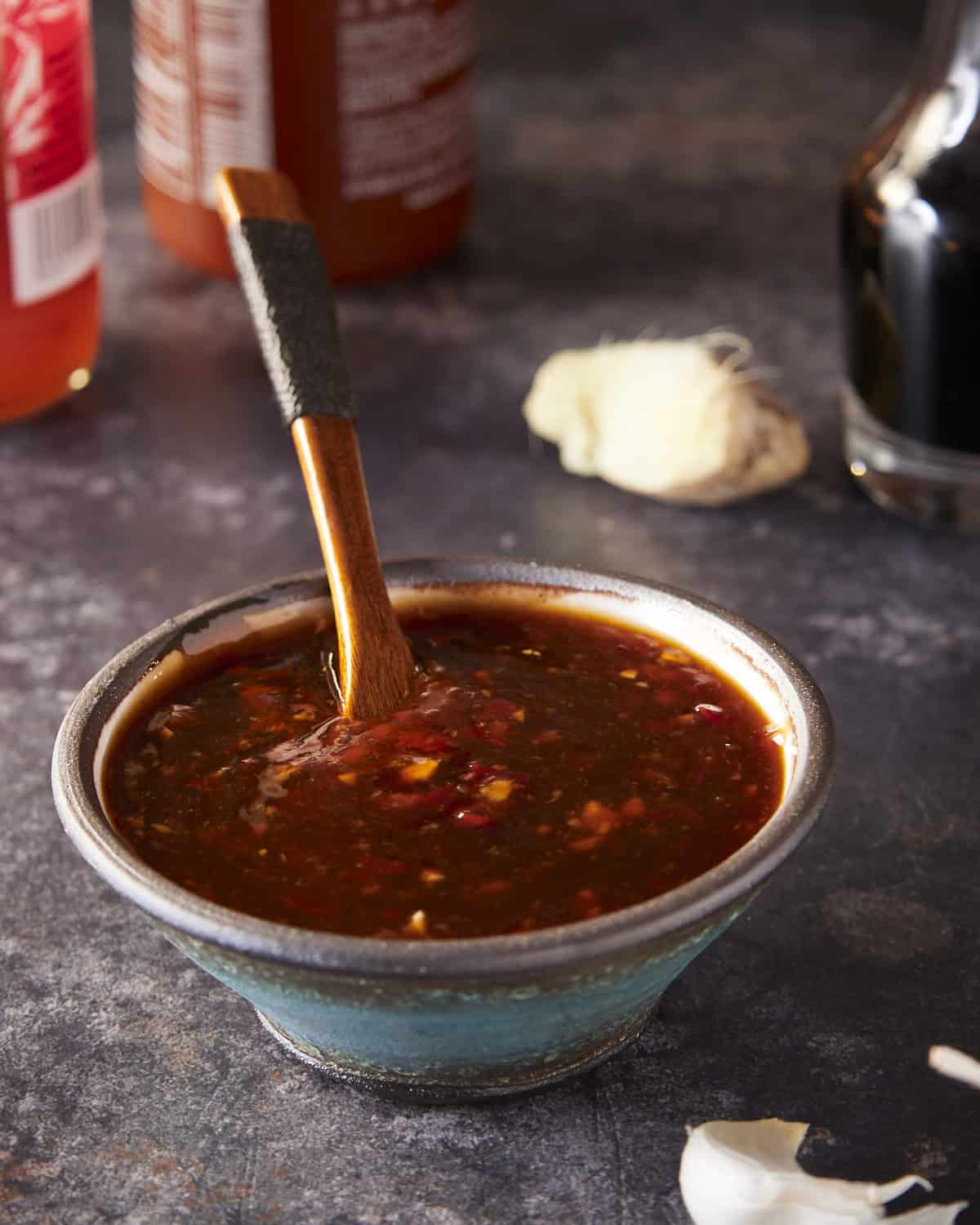 Sweet chili sauce in a bowl with a spoon, dripping the sauce into the bowl.